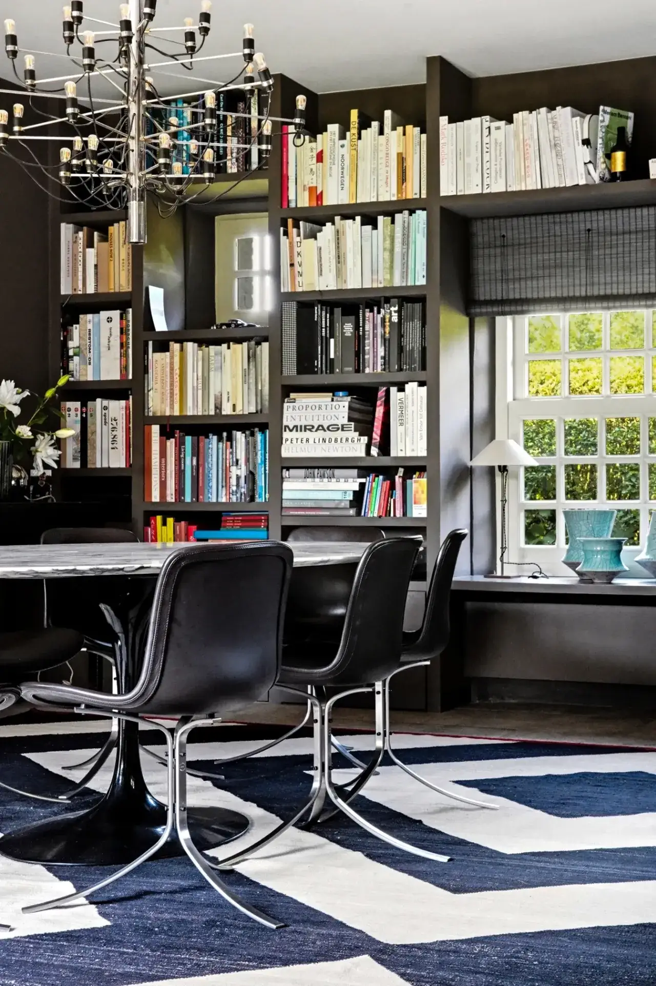 Woonkamer met grote ramen, boekenkast en zithoek